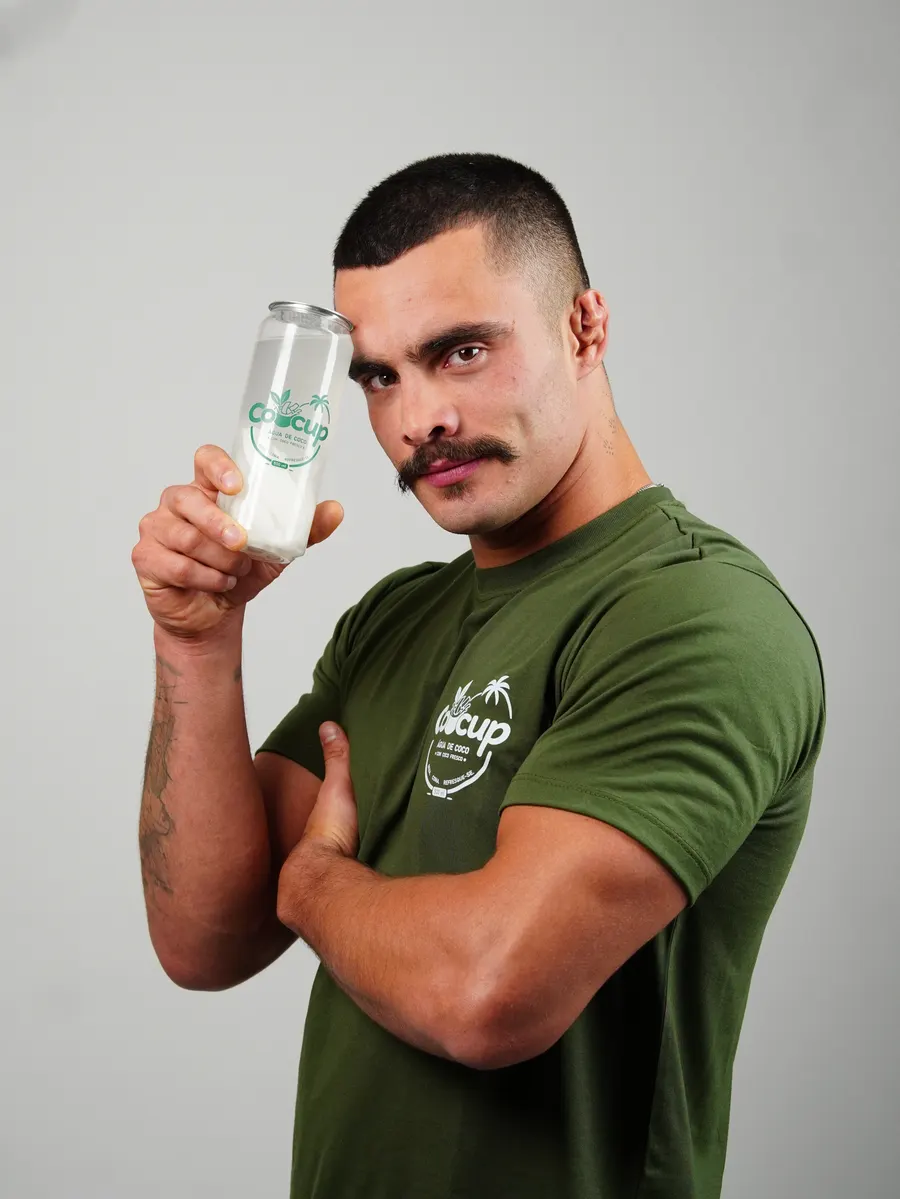 Homem inclinando a cabeça ao lado de um copo de Cocup