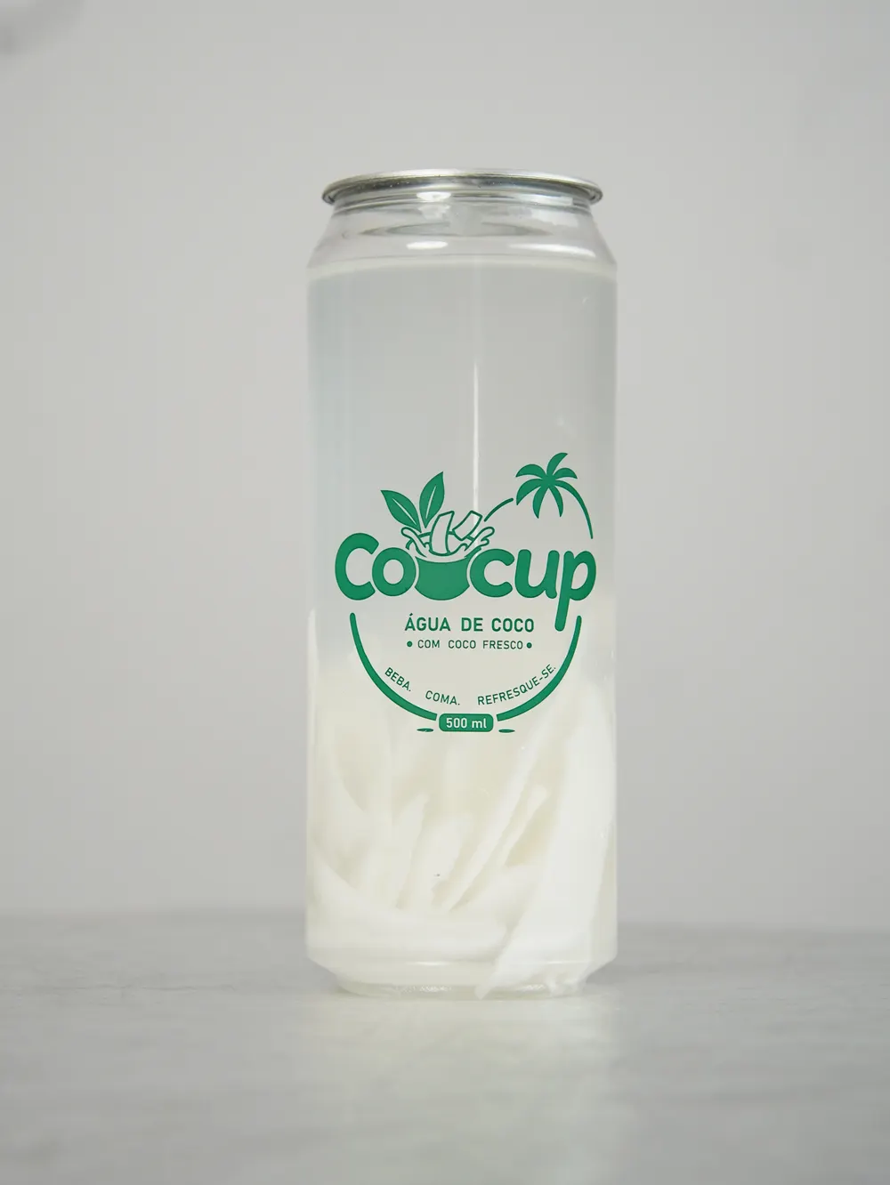 Copo de Cocup sobre bancada clara, com os pedaços de coco no fundo